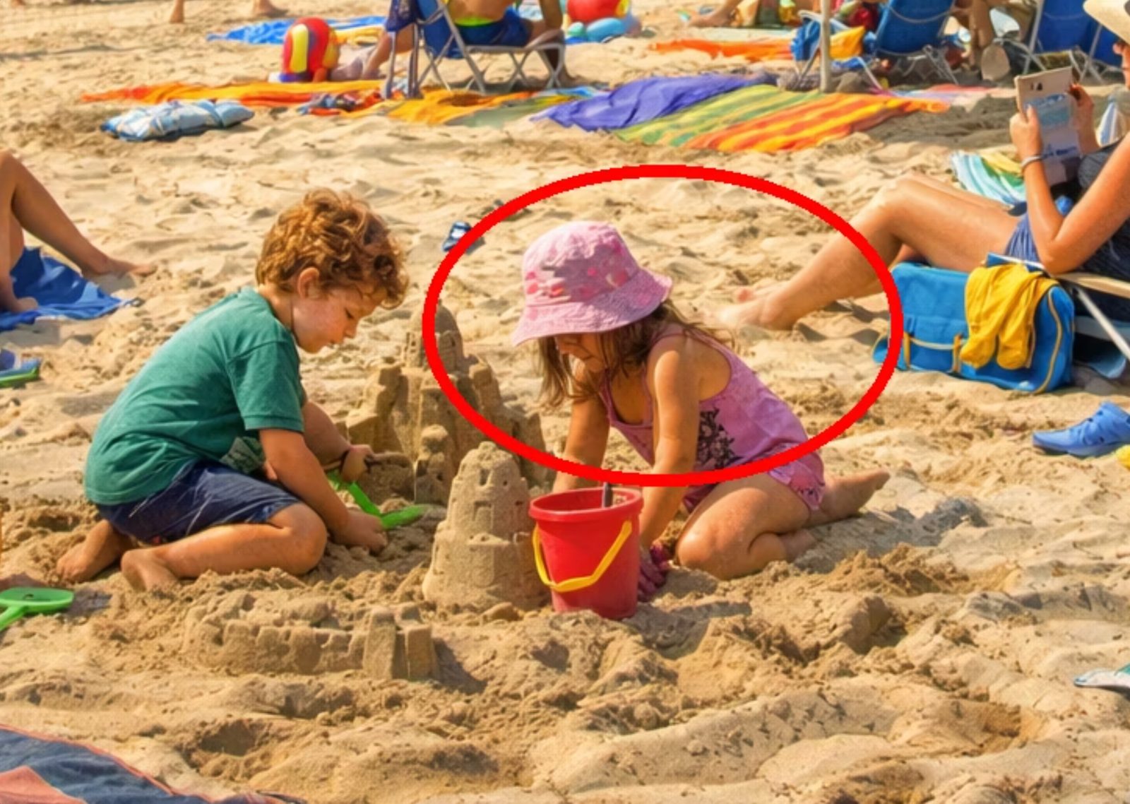 The same beach scene with a red circle drawn around two children building a sandcastle. There is no elephant inside the circle.